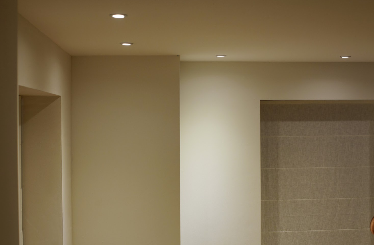 Interior room with recessed lights in the ceiling. White walls and a doorway.