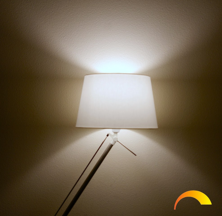 Lamp with white shade, light and beige wall.