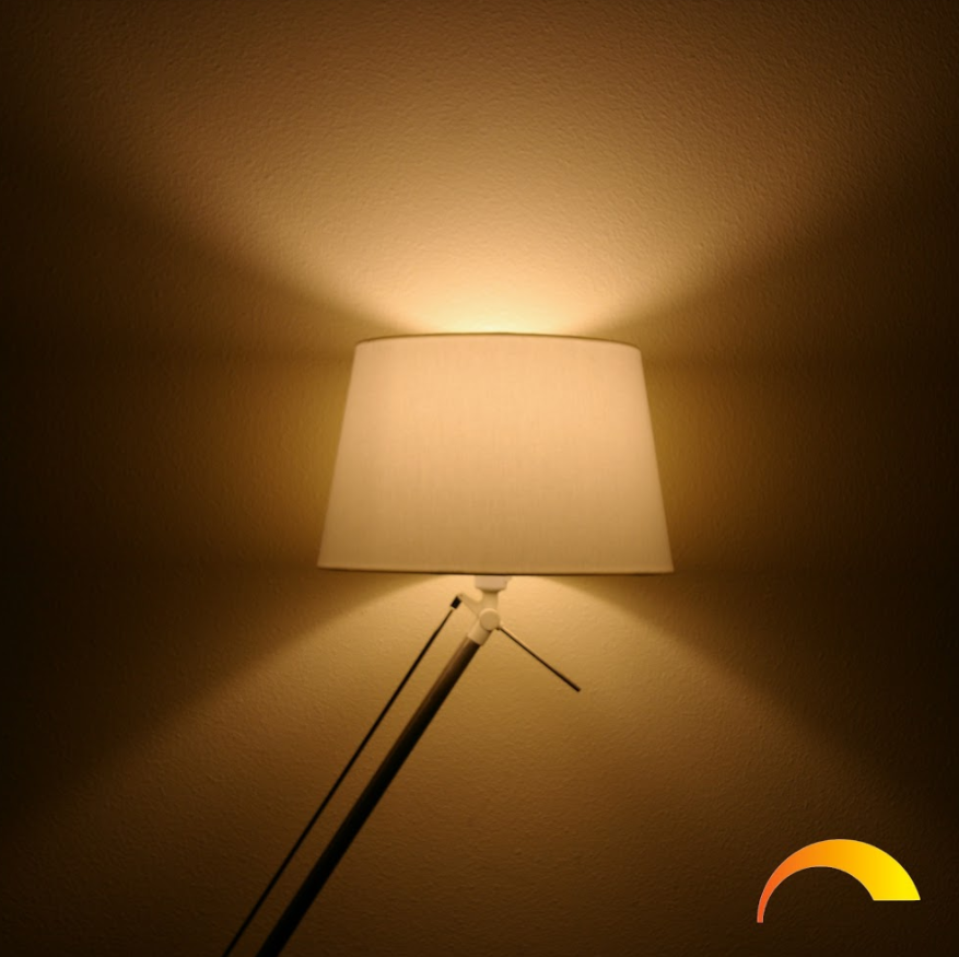 A lamp with a white shade casting light on a wall, with a sun icon.