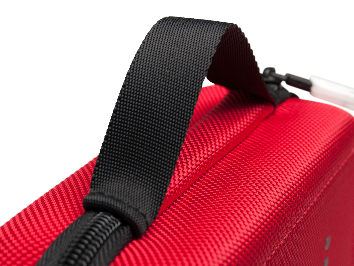 Nahaufnahme einer roten Tasche mit schwarzem Griff und Reißverschluss. Der Hintergrund ist schwarz.