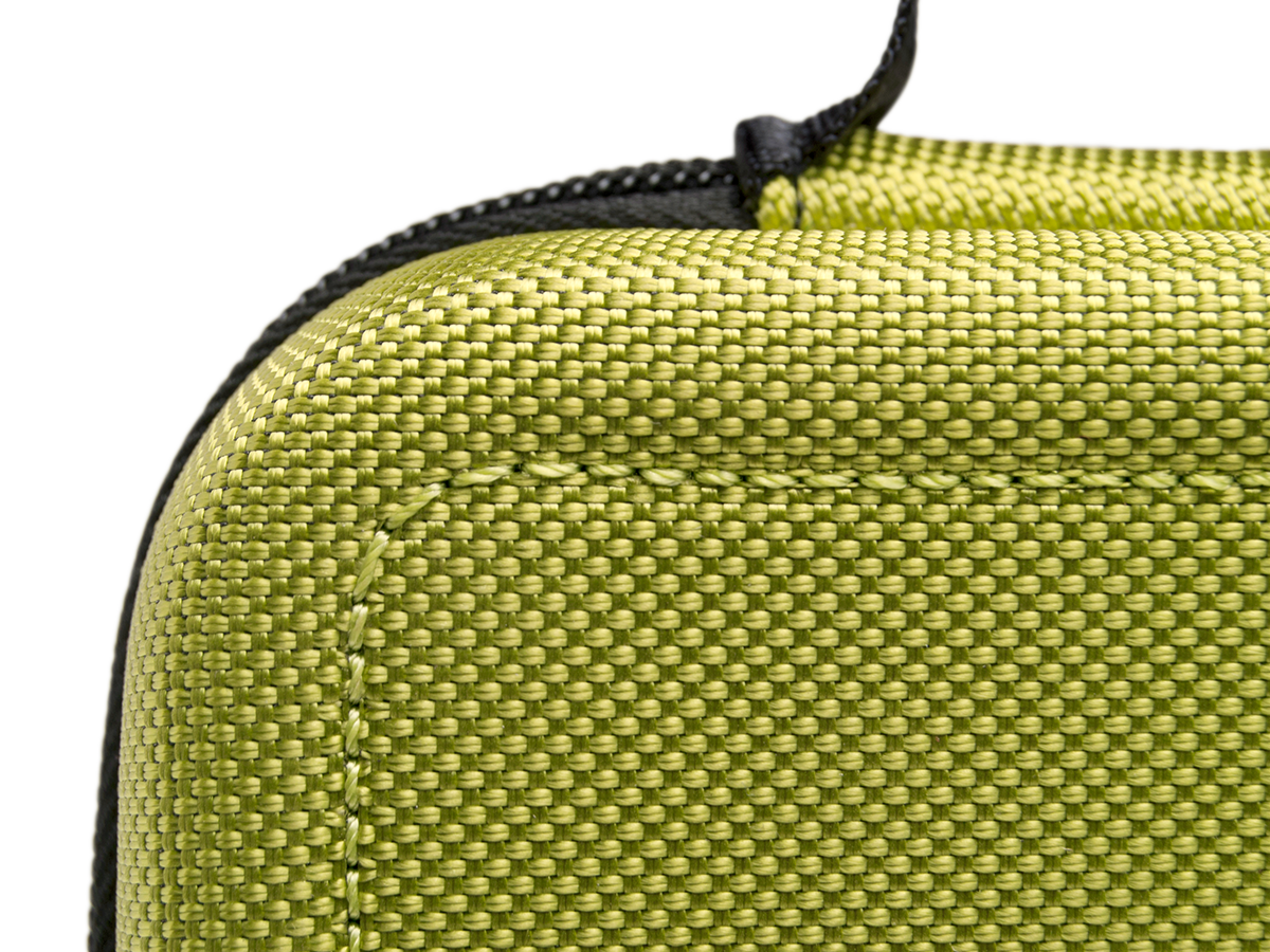 Nahaufnahme eines grünen, strukturierten Materials mit sichtbaren Nähten, die eine Ecke bilden.