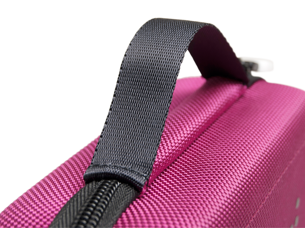 Nahaufnahme eines magentafarbenen Griffes einer Tasche. Schwarzer Reißverschluss ist sichtbar. Die Textur der Tasche ist auffällig.