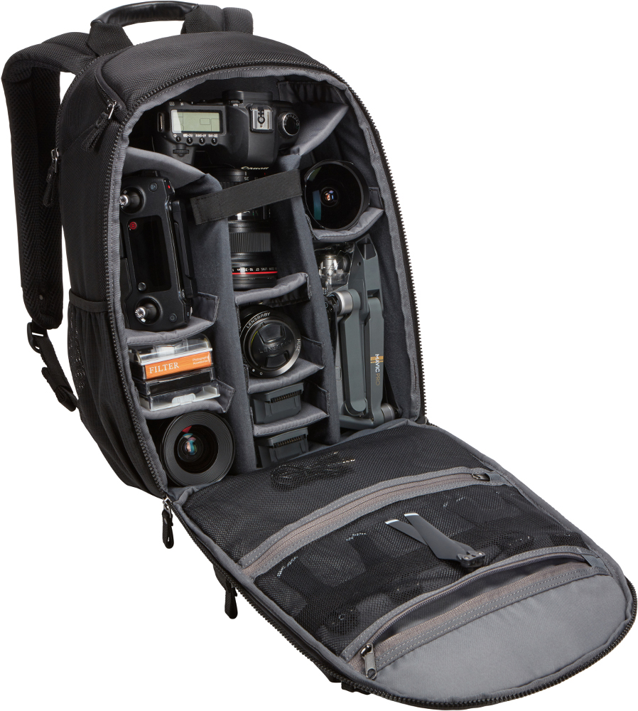 Black camera backpack open, filled with camera, drone, lenses, and accessories.