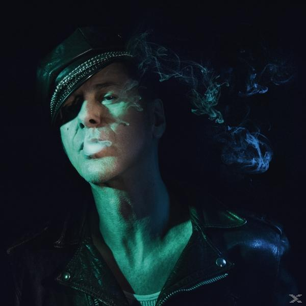 Homme en chapeau et veste en cuir fumant. Fond sombre avec lumières bleues et vertes.