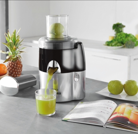 Presse-agrumes avec du jus vert versé dans un verre. Ananas, pommes et livre de cuisine.