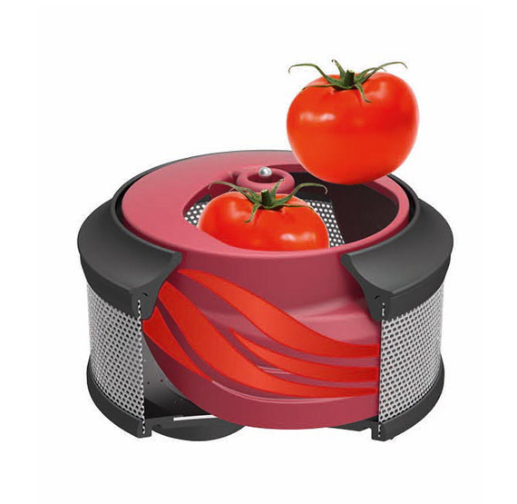 Une tomate rouge tombe dans la machine à broyer les tomates. Une autre tomate est dans la machine.