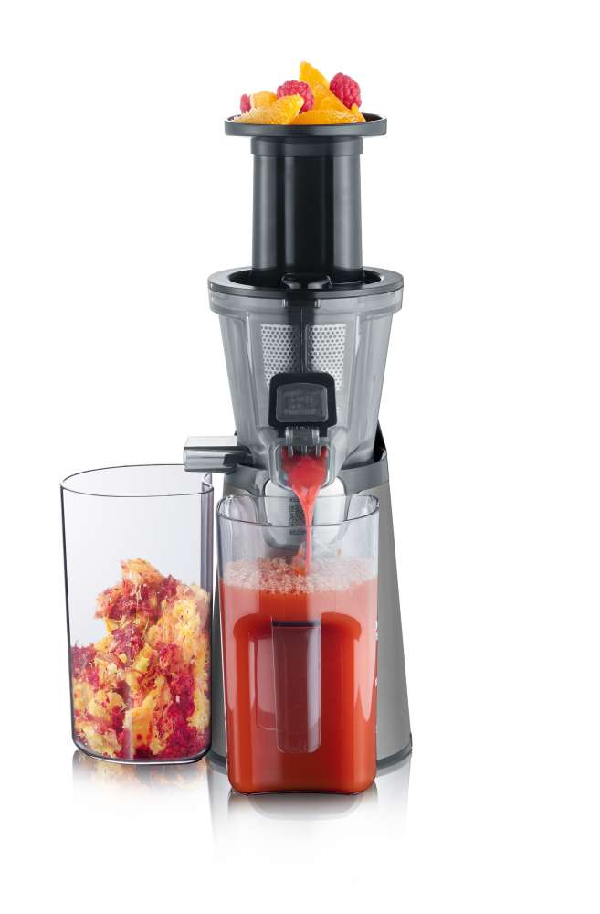Juicer with juice and pulp containers. Red juice flowing. Fruit on top. White background.