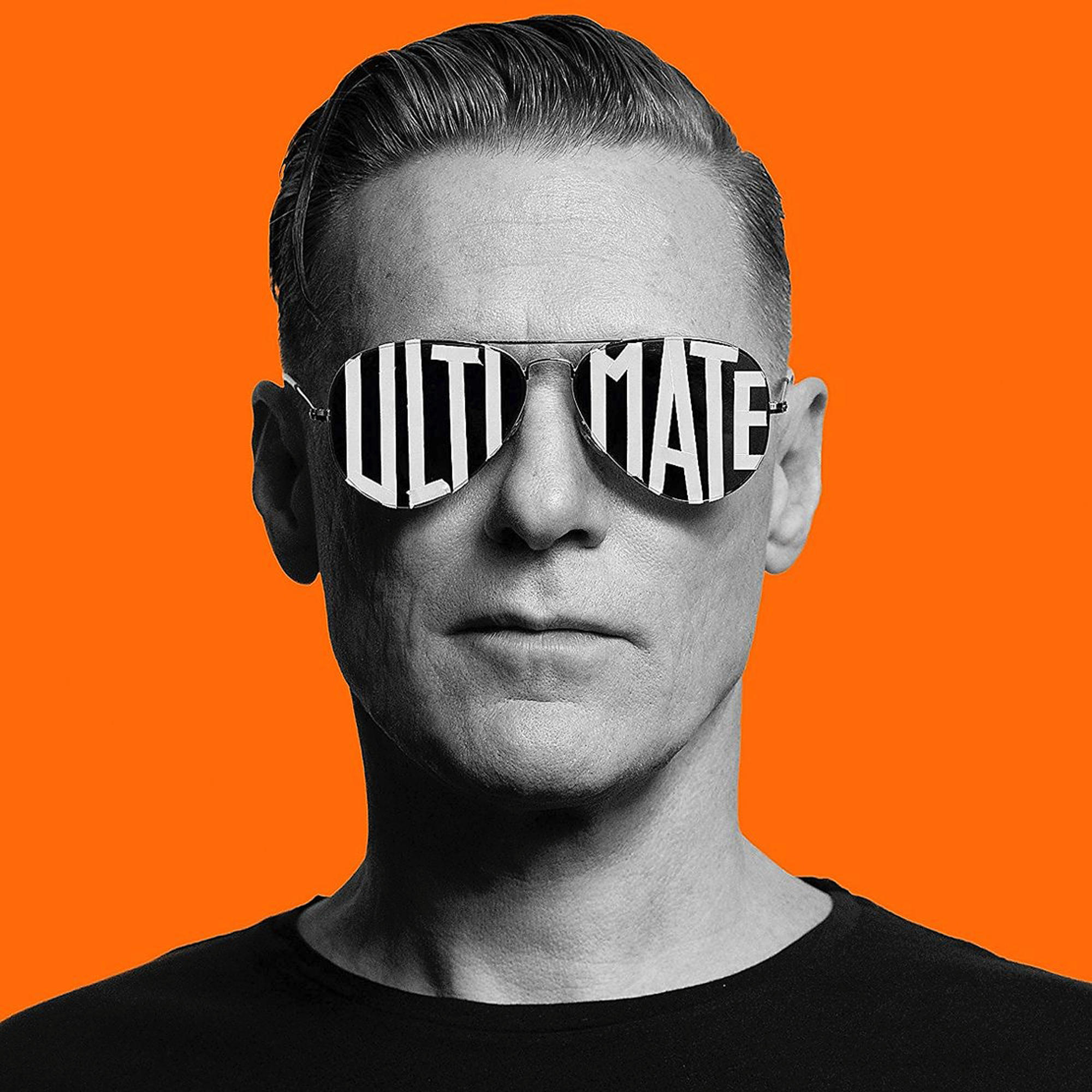 Mann mit Sonnenbrille, auf deren Gläsern das Wort 'ULTIMATE' gespiegelt wird, orangefarbener Hintergrund.