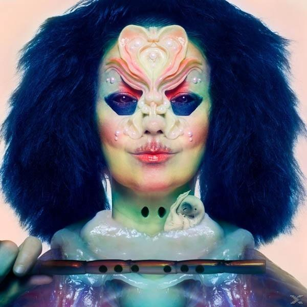 Frau mit Gesichtsmaske, dunklem Haar, hält eine Flöte. Blasse Haut, rosa Hintergrund.
