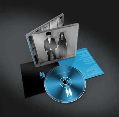 CD tok két ember fotójával, egy CD-vel és egy füzettel, sötét felületen.