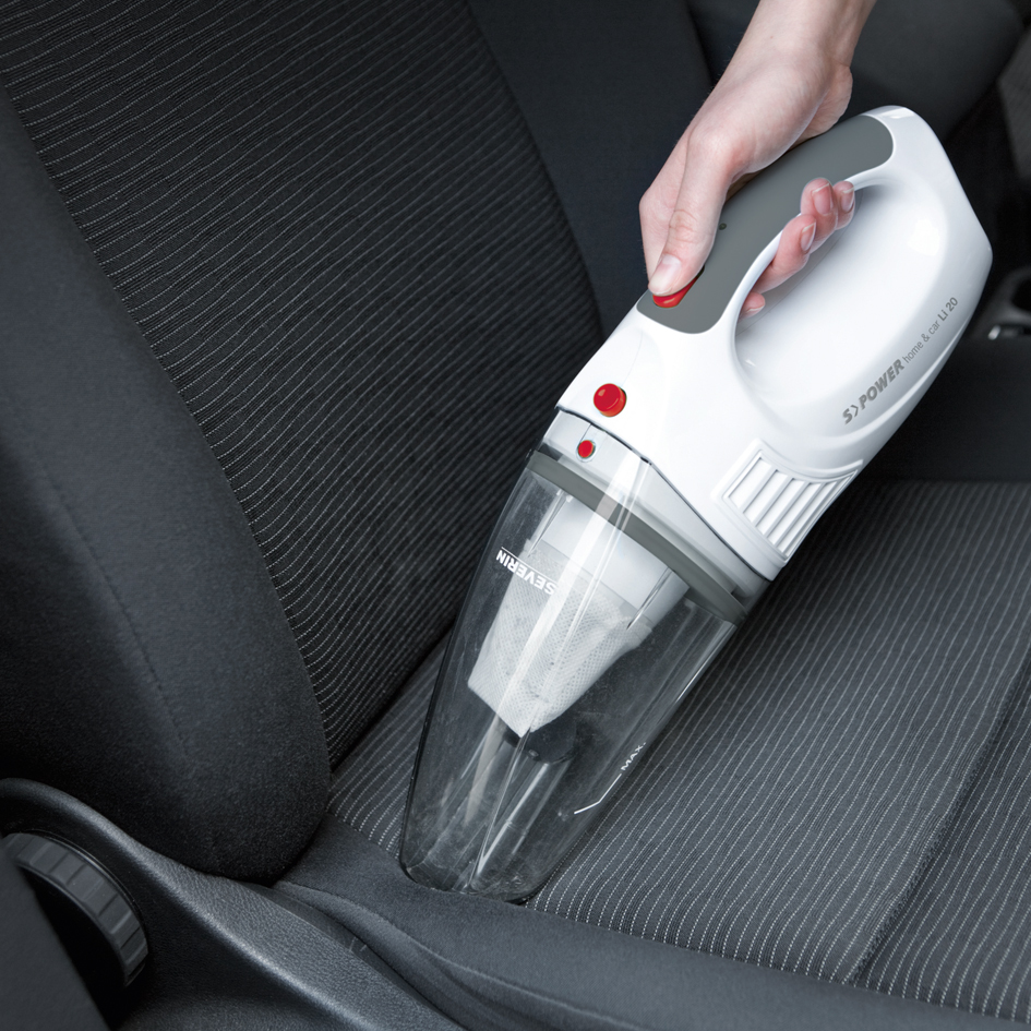 Une main utilisant un aspirateur de voiture portable blanc et gris.