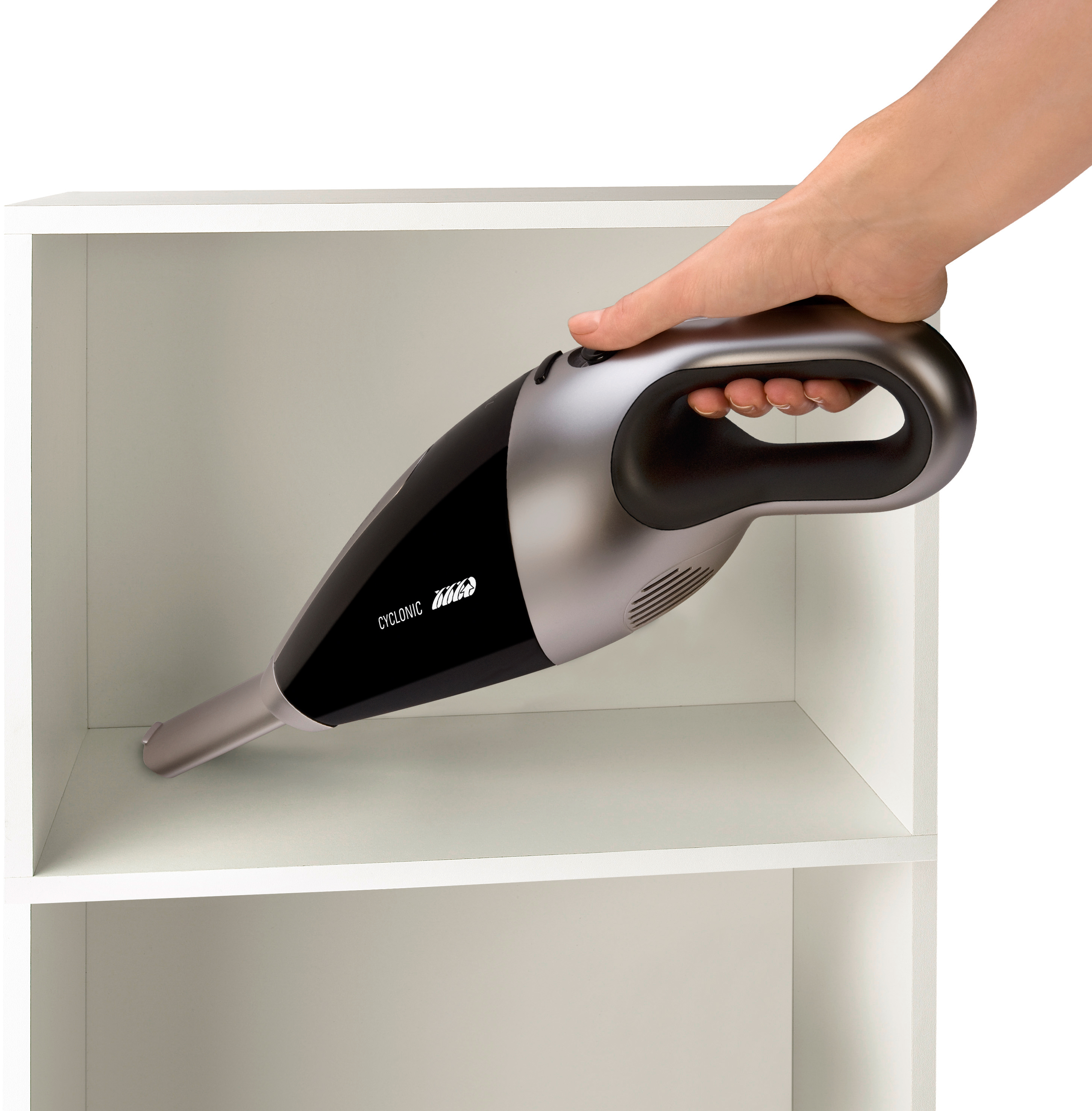 Hand die een handheld stofzuiger gebruikt om in een witte kastplank schoon te maken.