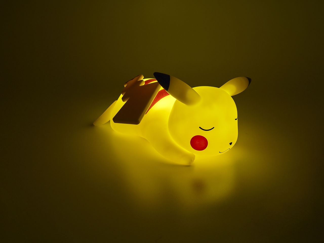Eine leuchtend gelbe Pikachu-Figur, die mit geschlossenen Augen liegt.