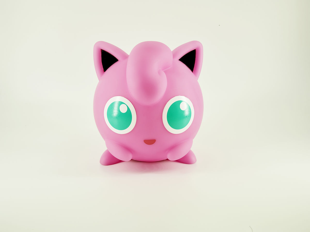 Une figurine rose de Jigglypuff Pokemon sur une surface blanche.