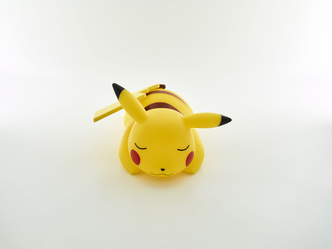 Pikachu-Figur in Schlafpose, gelb, mit roten Wangen und schwarzen Spitzen.