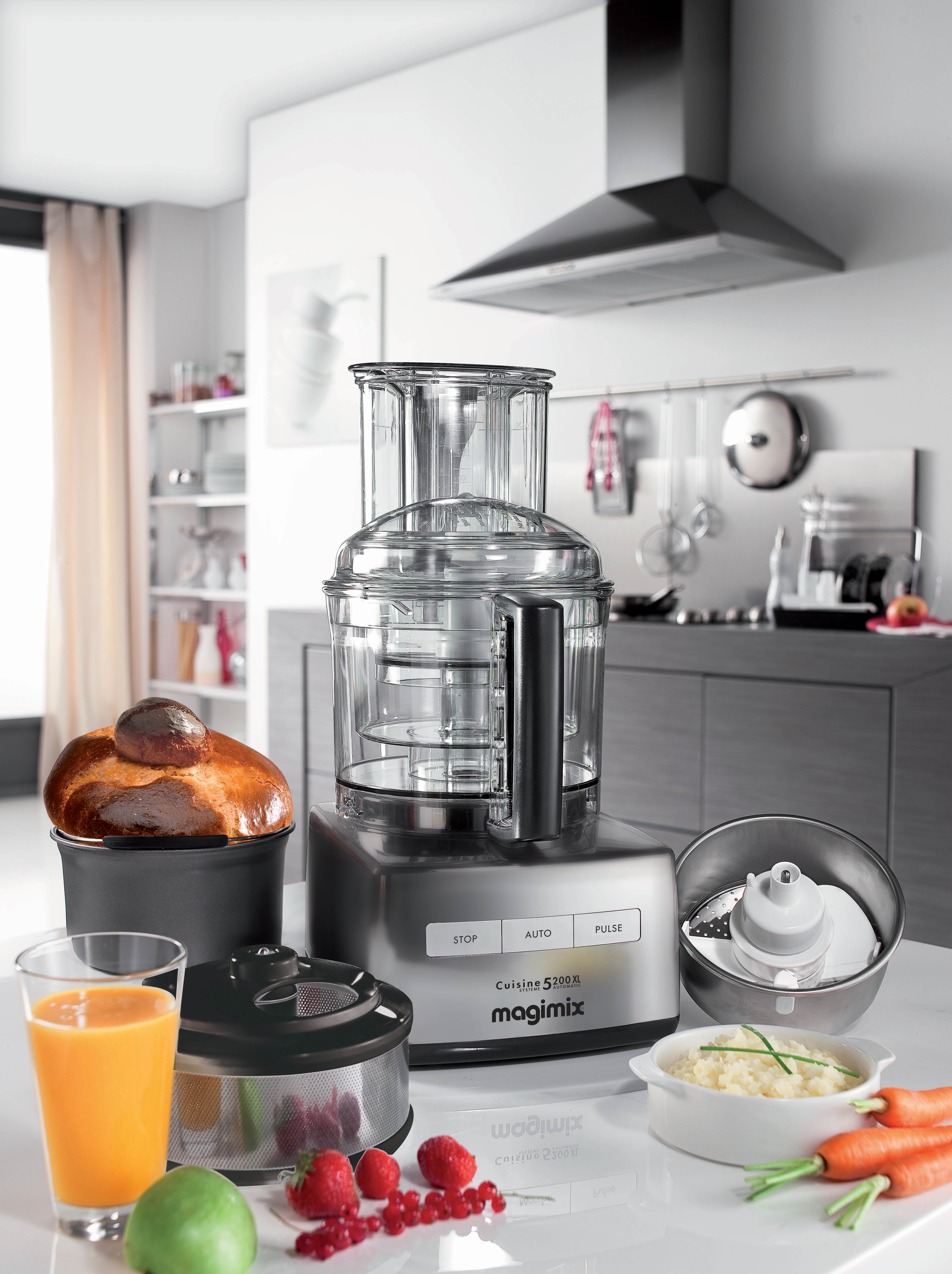 Robot culinaire avec accessoires et ingrédients comme du pain et des fruits.