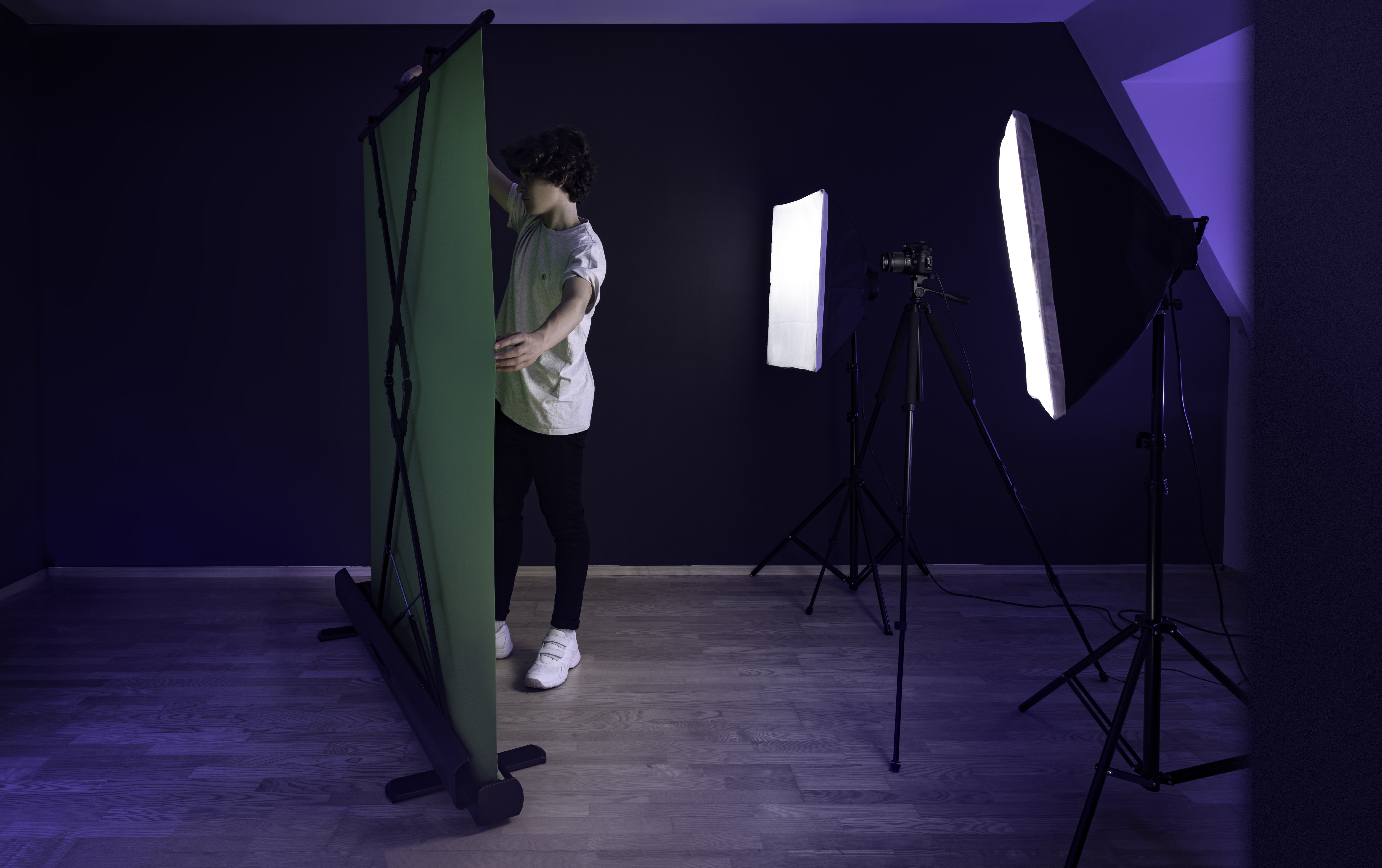 Person richt einen Greenscreen in einem Studio mit Lichtern und Ausrüstung ein.