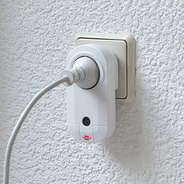 Weißer Smart Plug, der in einer Wandsteckdose an einer strukturierten Wand steckt.