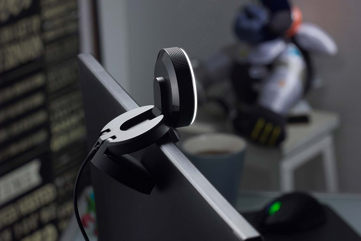 Webcam an einem Computermonitor befestigt. Ein weißer Schreibtisch und andere Gegenstände sind im Hintergrund unscharf.