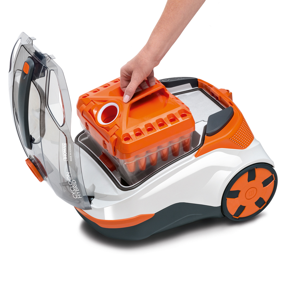Eine Person, die den Wassertank aus einem orangefarbenen und weißen Staubsauger entfernt.
