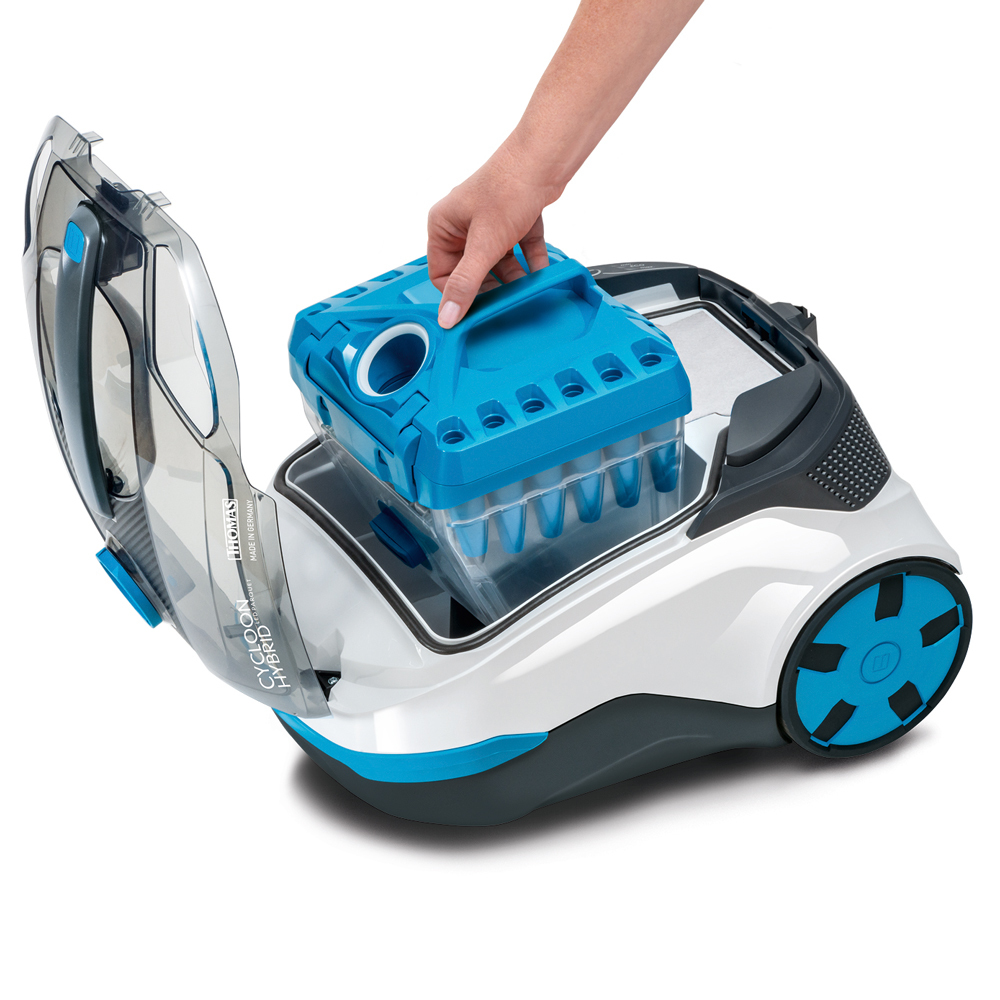 Eine Person legt einen blauen Behälter in einen Staubsauger. Der Staubsauger ist weiß und blau.