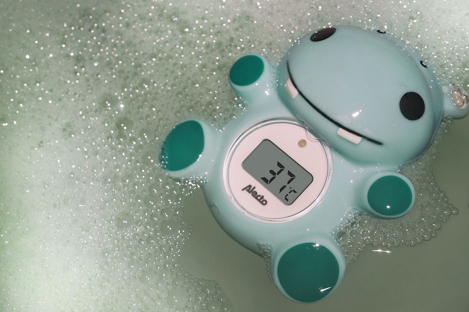 A blue hippo-shaped bath toy with a digital thermometer displaying 37.1 degrees in soapy water.