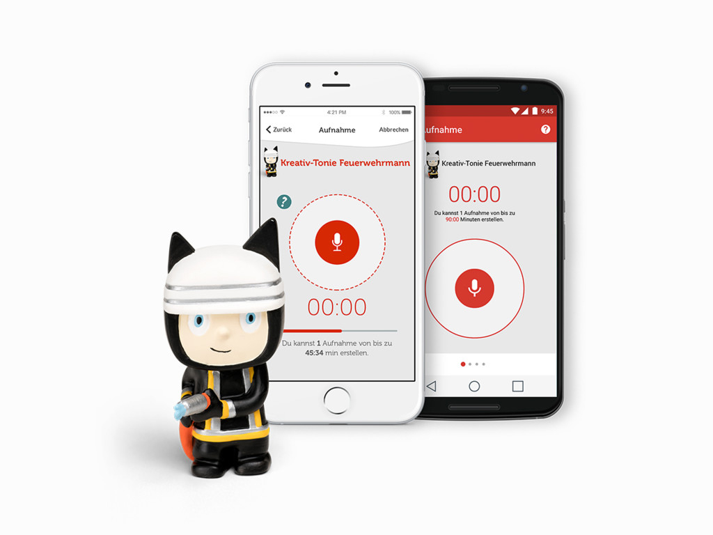 Zwei Smartphones, die Aufnahme-Apps anzeigen, und ein Spielzeugfeuerwehrmann auf weißem Untergrund.