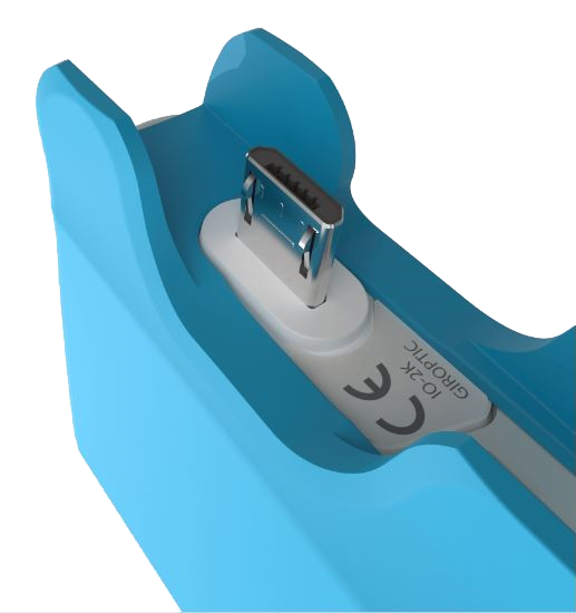 A close-up of a blue charging dock with a silver USB-C connector. The dock has a white base and a label with text.