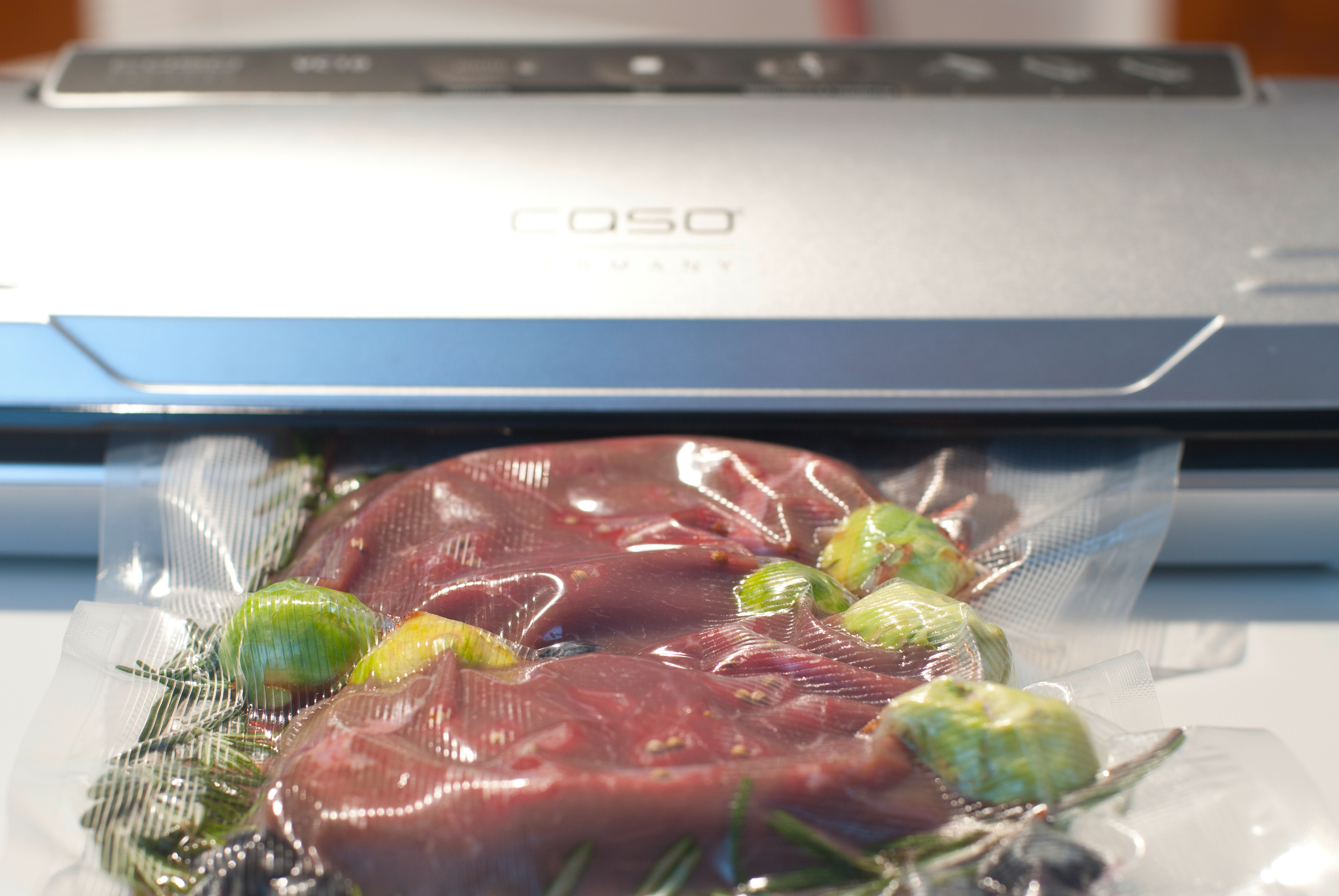 Essen in einem Vakuumbeutel, versiegelt von einer Maschine. Gemüse und Fleisch sind sichtbar.