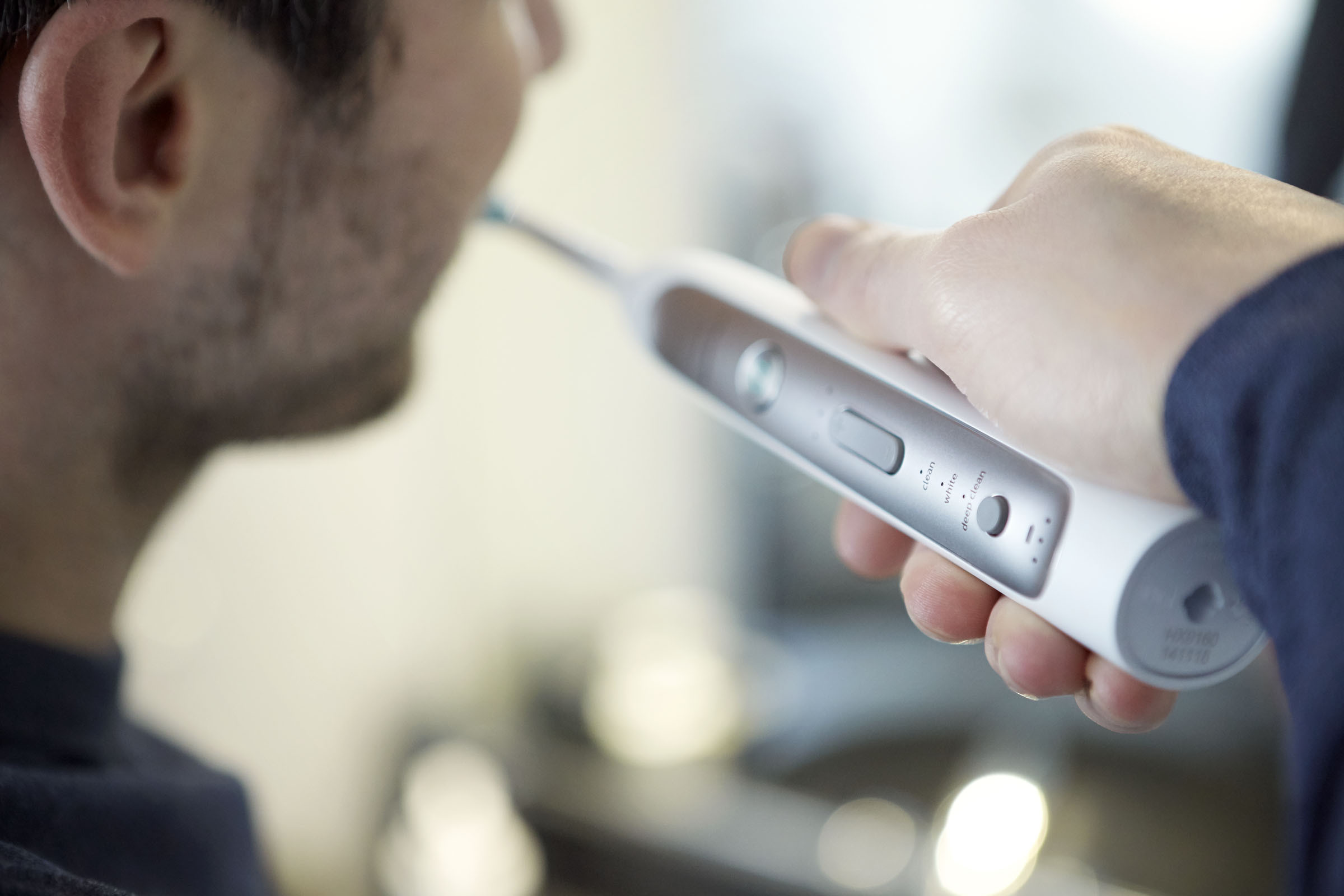 Person putzt sich mit einer elektrischen Zahnbürste die Zähne, Nahaufnahme.