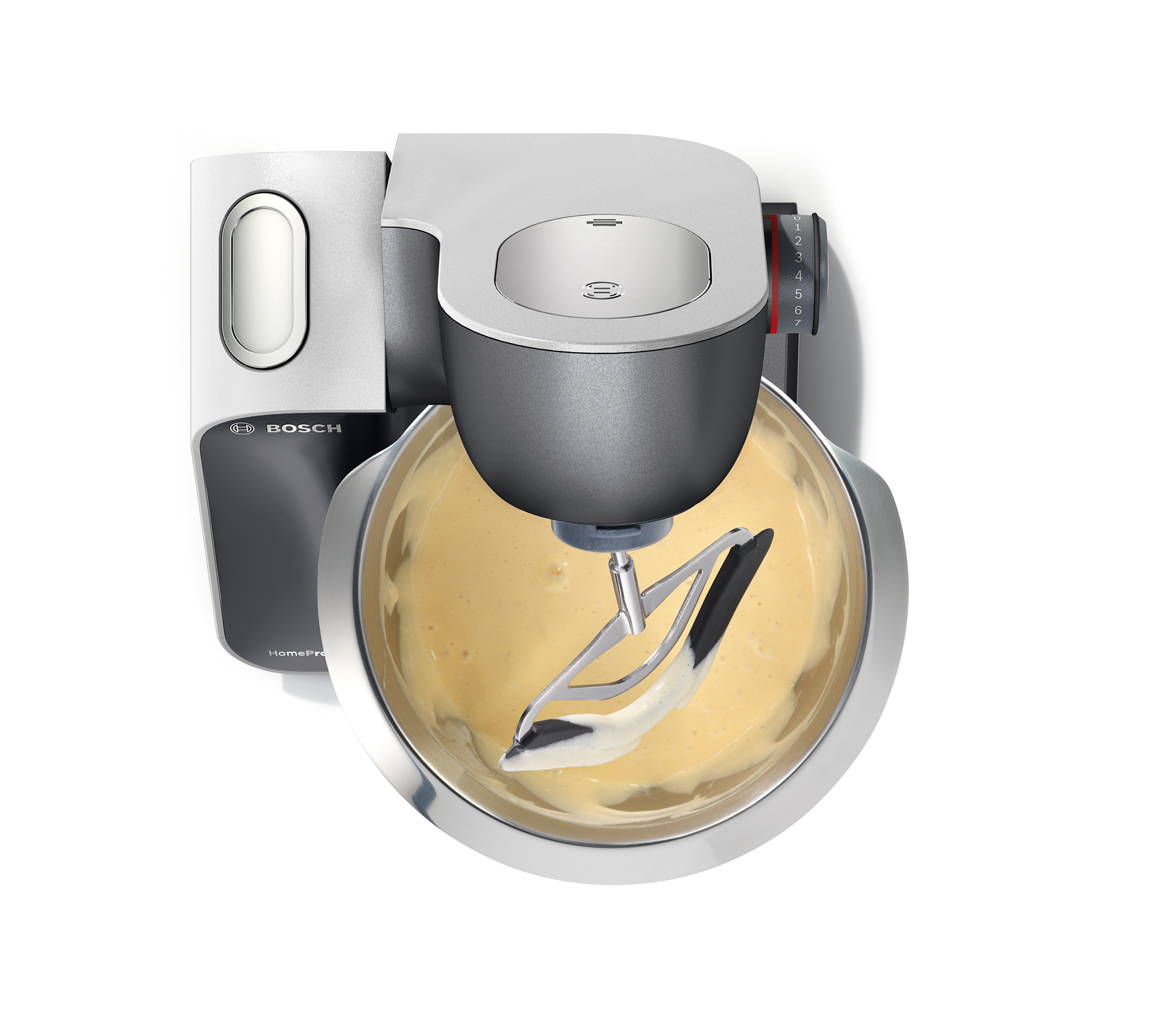 Bosch kitchen machine mixing batter in a stainless steel bowl, top view.