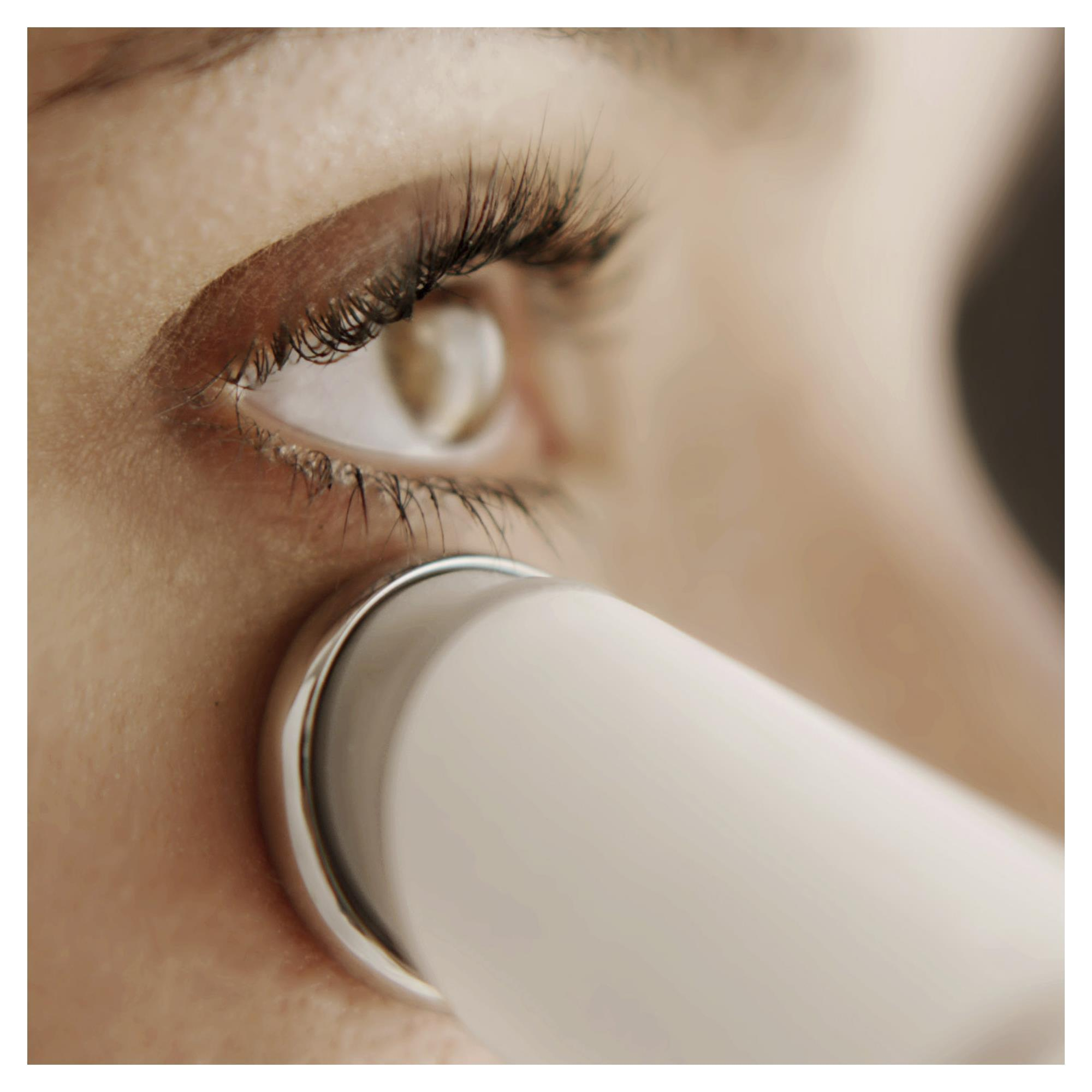 Ein Auge mit langen Wimpern, das mit einem Schönheitsgerät behandelt wird.