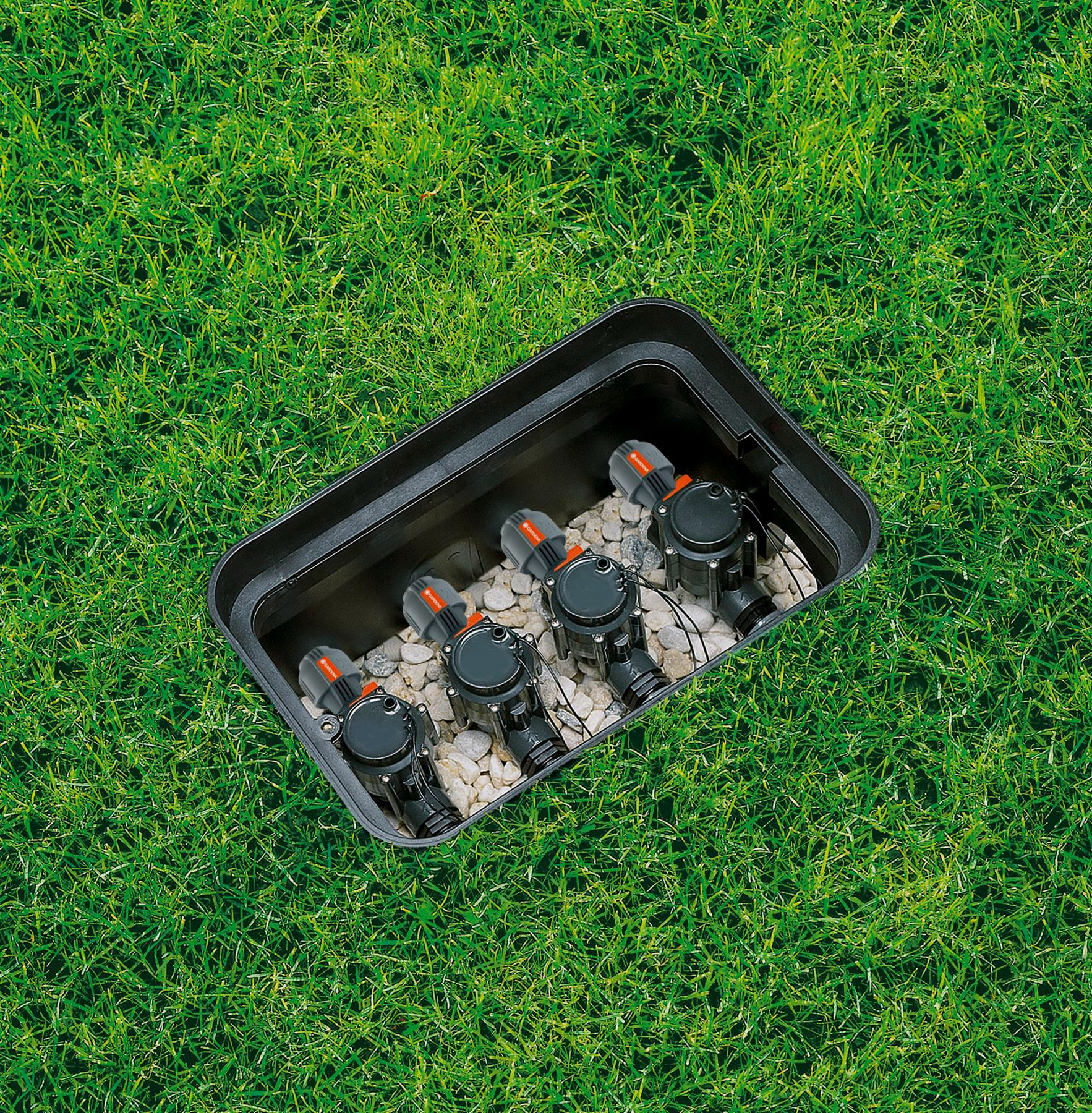 Schwarze rechteckige Box mit Sprinklern im Inneren, auf grünem Gras.