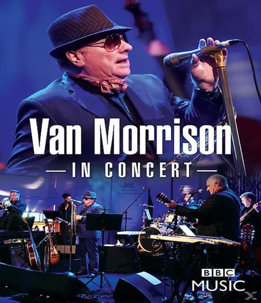Van Morrison live, singt in ein Mikrofon. Eine Band begleitet ihn auf der Bühne.