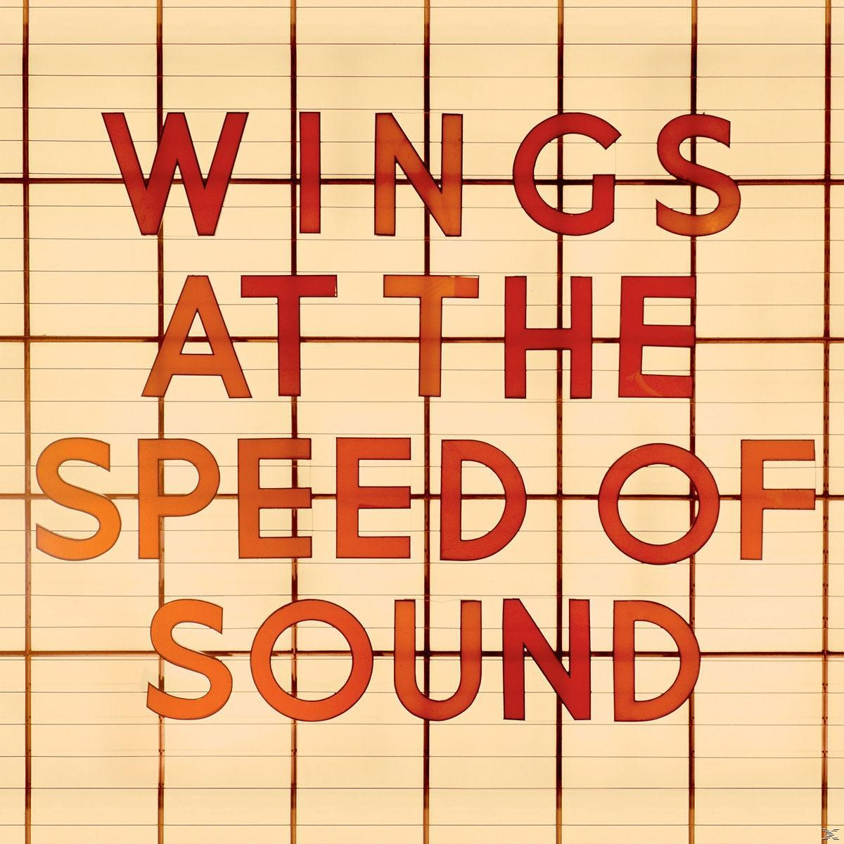 Pochette d'album avec les mots 'WINGS AT THE SPEED OF SOUND' en orange sur fond quadrillé jaune.