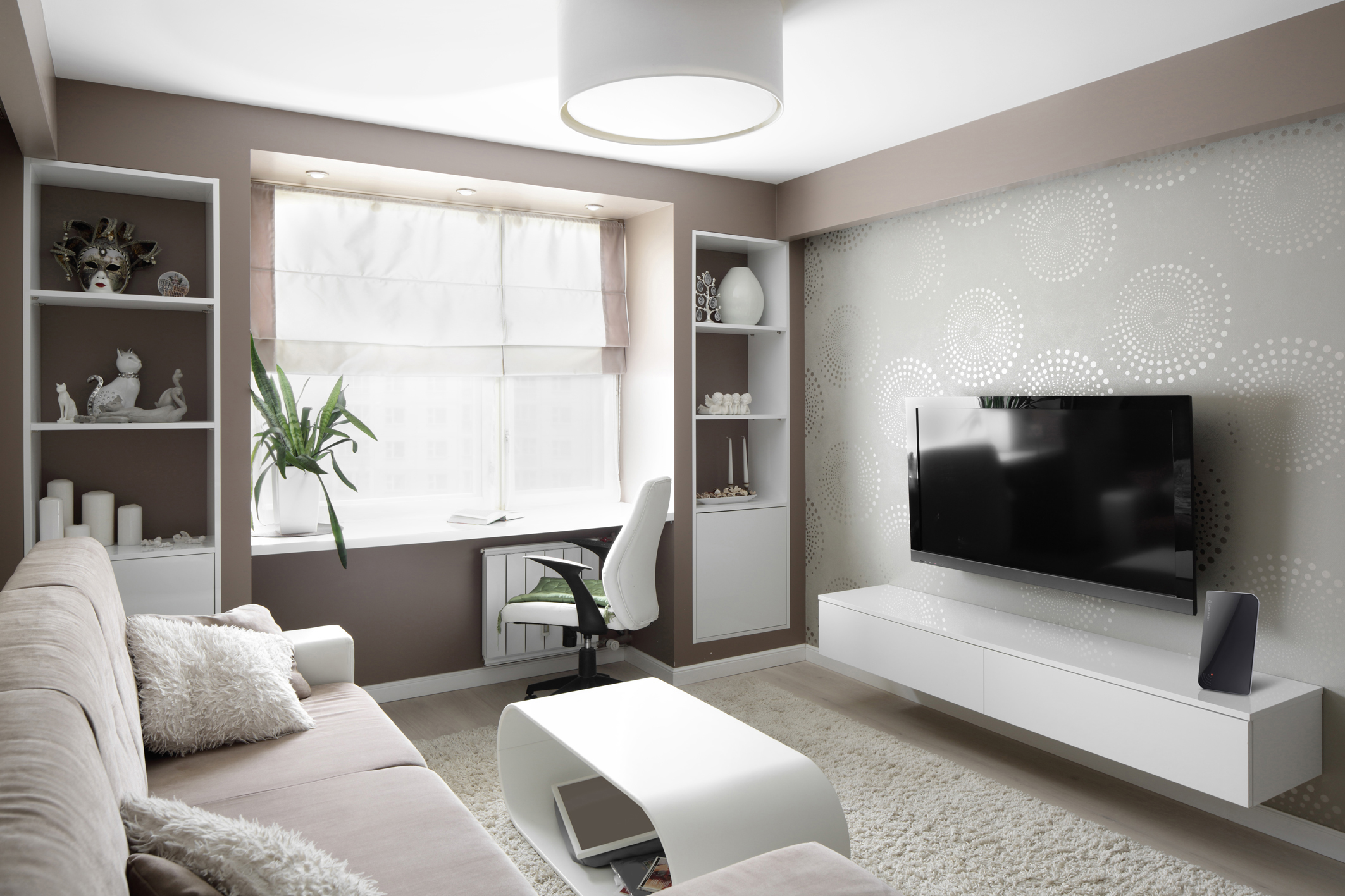 Modernes Wohnzimmer mit weißen Möbeln, beigen Wänden und einem großen Fernseher.
