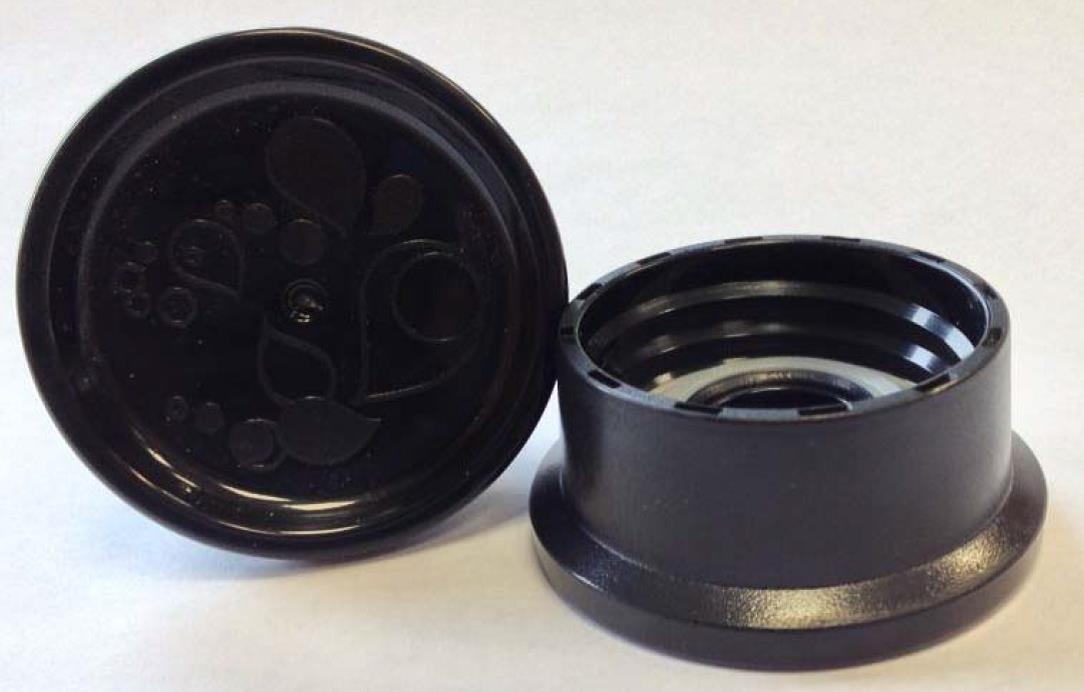 Zwei schwarze Kunststoffteile, ein Deckel und ein Sockel, einer Komponente einer Kaffeemaschine.