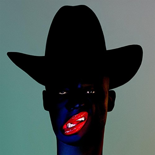 Une personne à la peau noire, portant un chapeau de cowboy noir et du rouge à lèvres rouge.