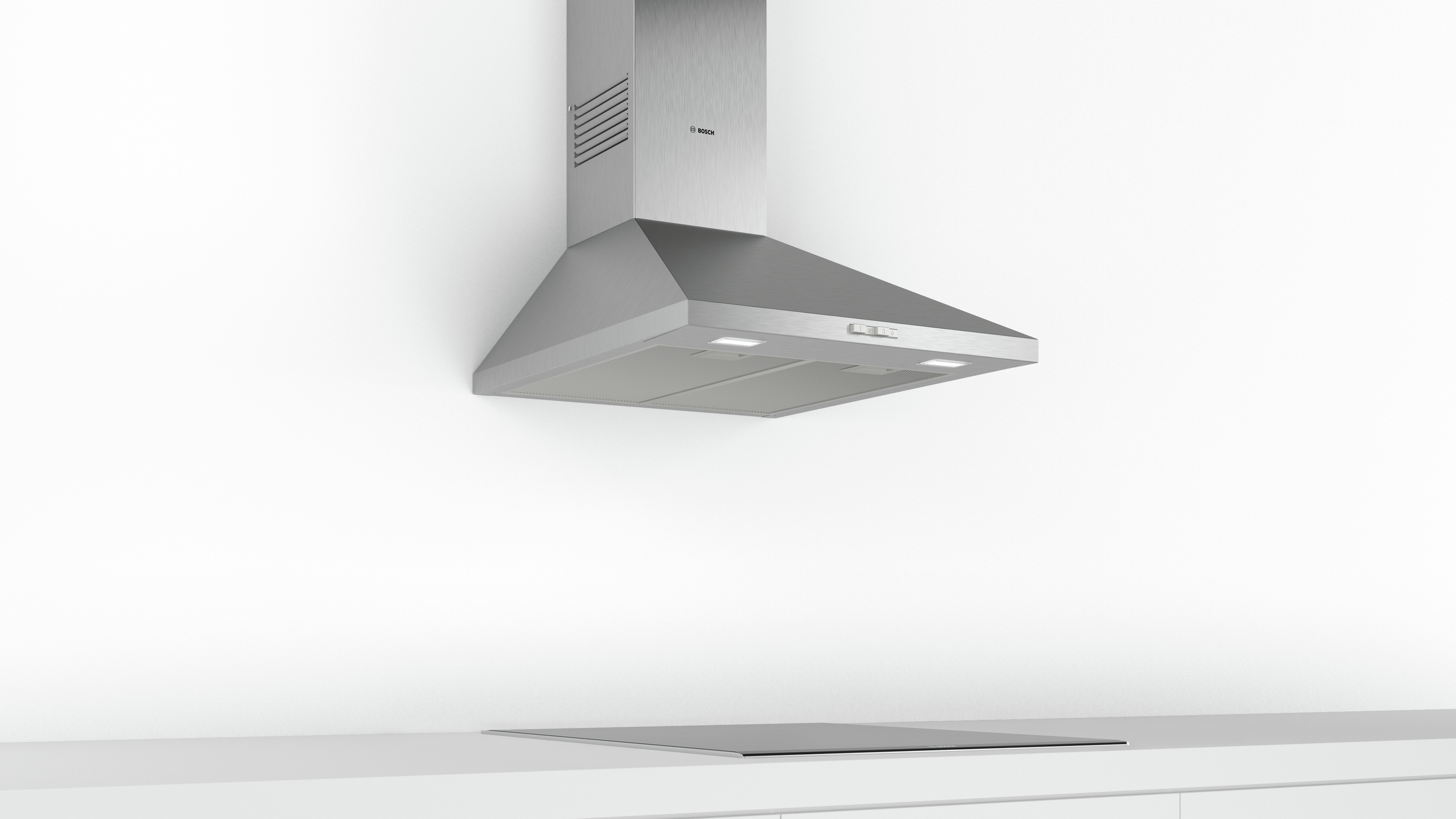 Stainless steel range hood above a ceramic cooktop. White walls and counter complete the kitchen scene.