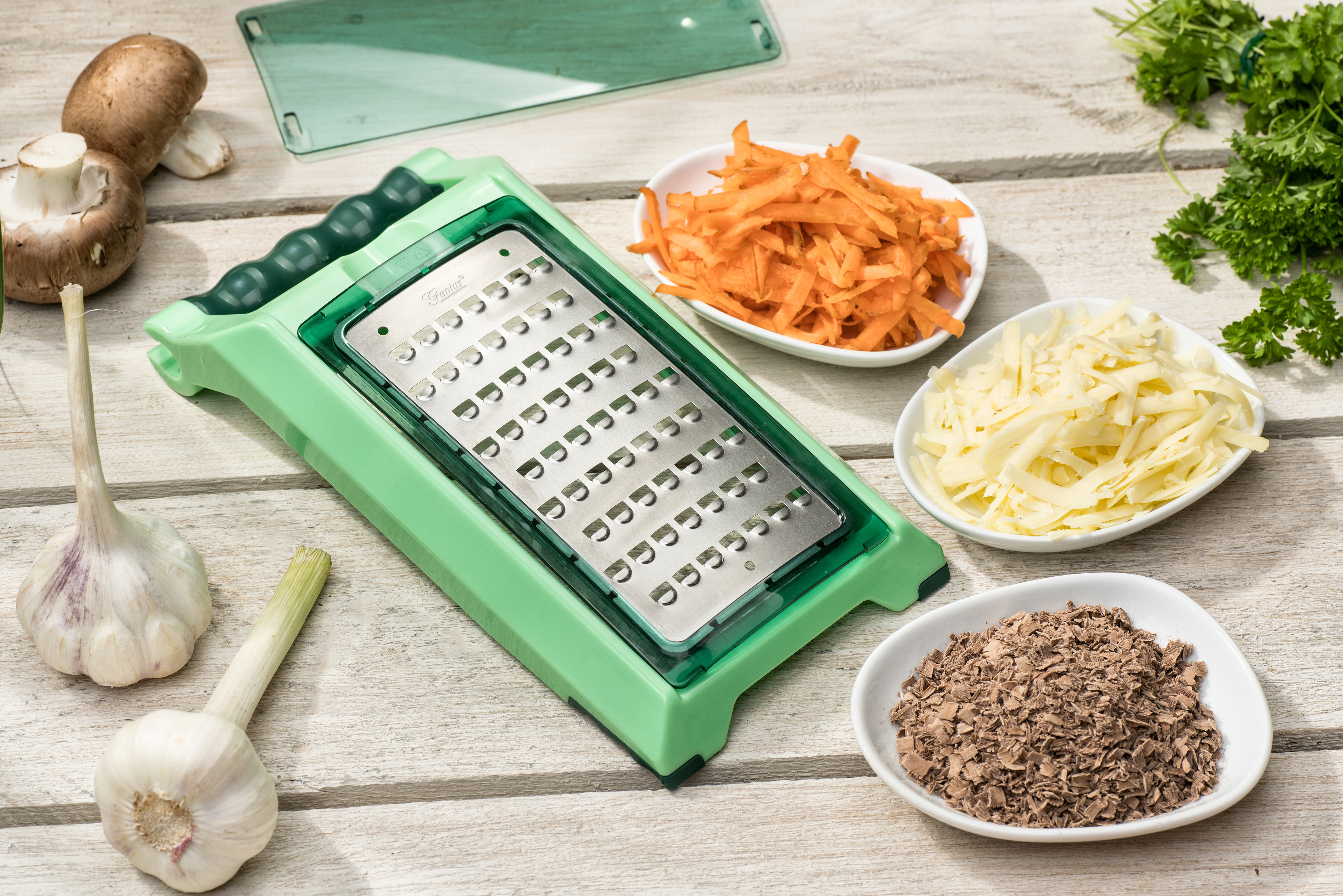 Grüner Reibeisen mit Gemüse und Zutaten auf einer Holzoberfläche.