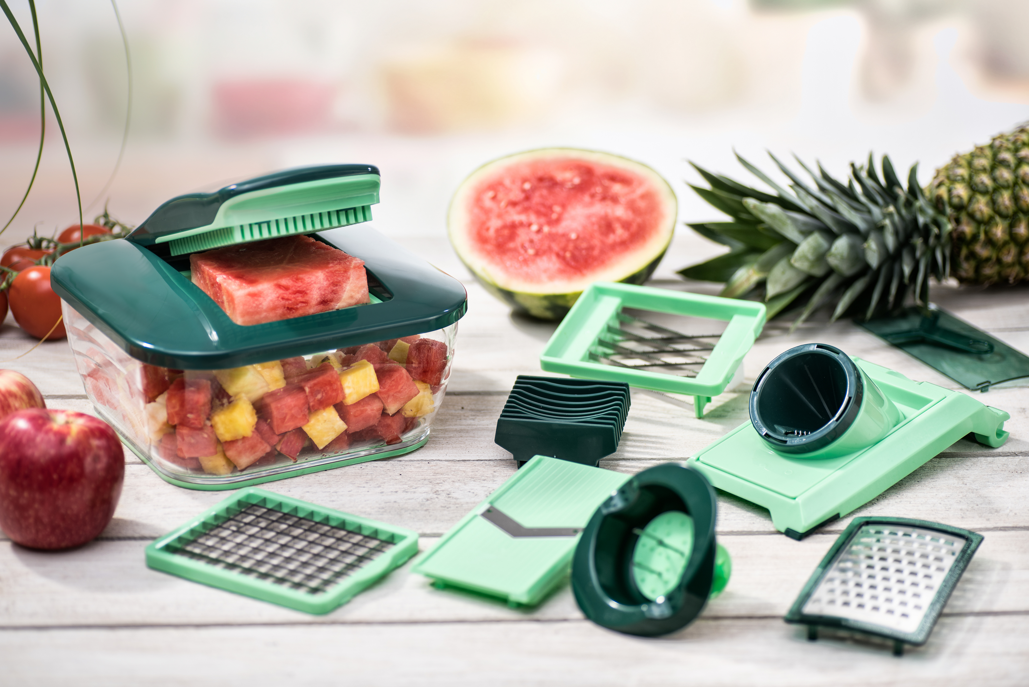 Lebensmittelzubereitungsset mit gewürfelten Wassermelonen, Ananas und verschiedenen Werkzeugen auf Holz.