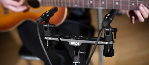 Zwei Mikrofone nehmen eine Gitarre auf, die von einer Person gespielt wird.