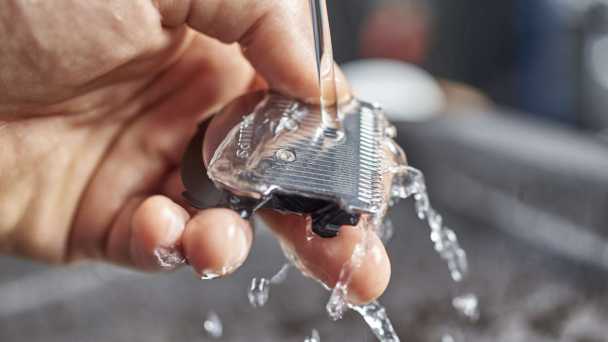 Hand spült einen transparenten Philips Rasiererkopf mit Wasser ab. Nahaufnahme, nass und sauber.