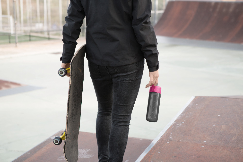 Person with skateboard and water bottle at skatepark.