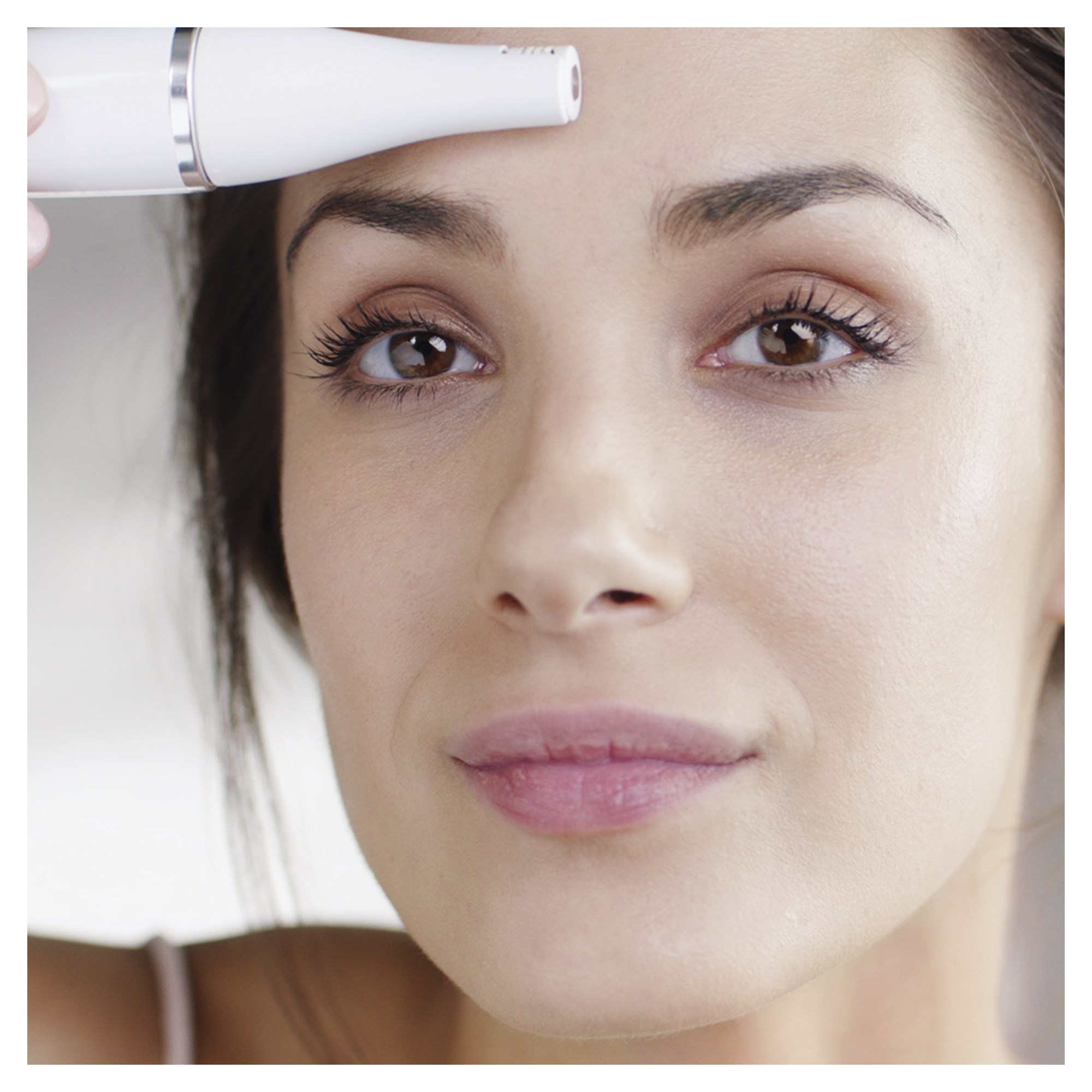 Une femme aux yeux bruns et un appareil blanc près de son visage.