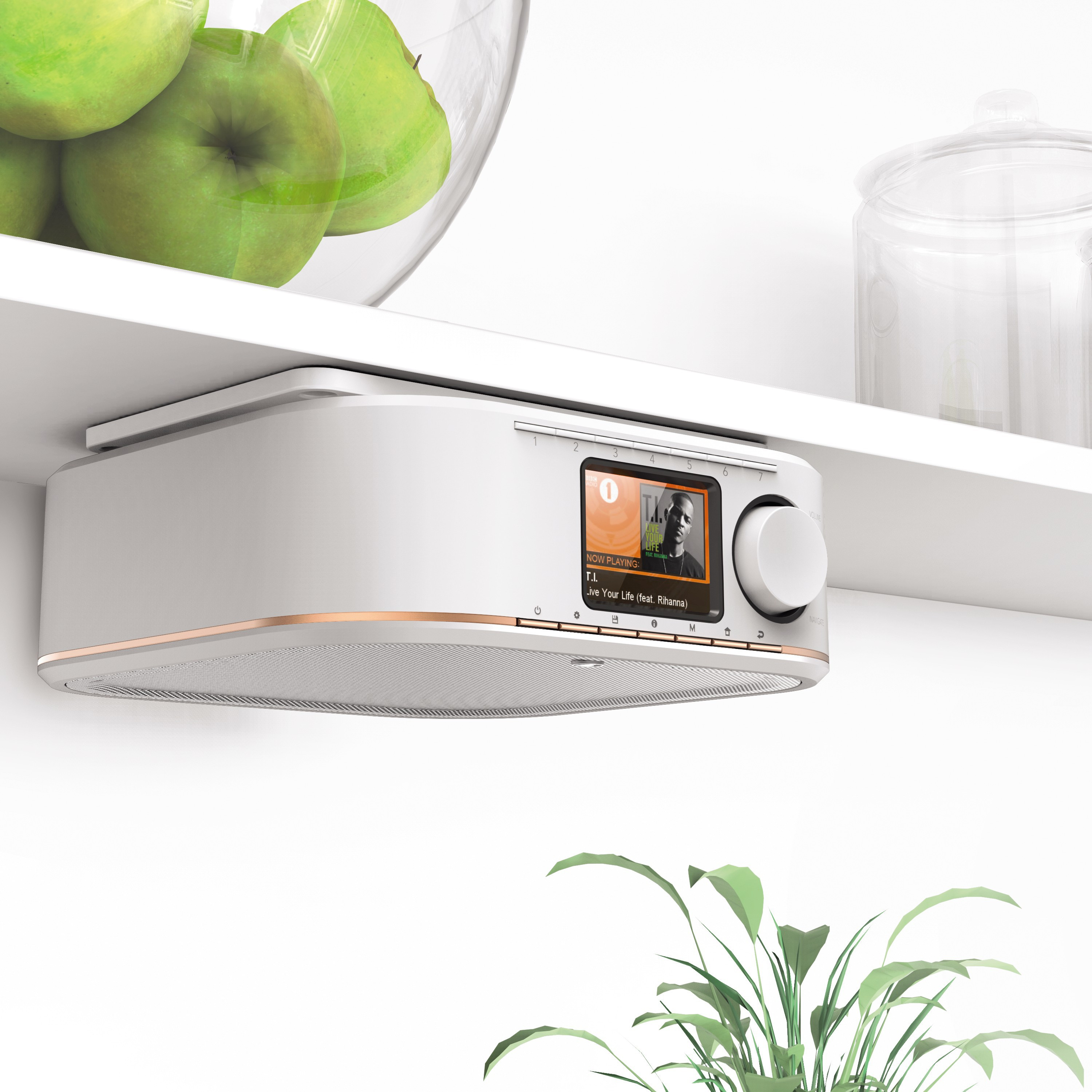 Weißes Radio unter einem Regal montiert. Anzeige zeigt einen Song von T.I. mit Rihanna. Grüne Äpfel und Glas.
