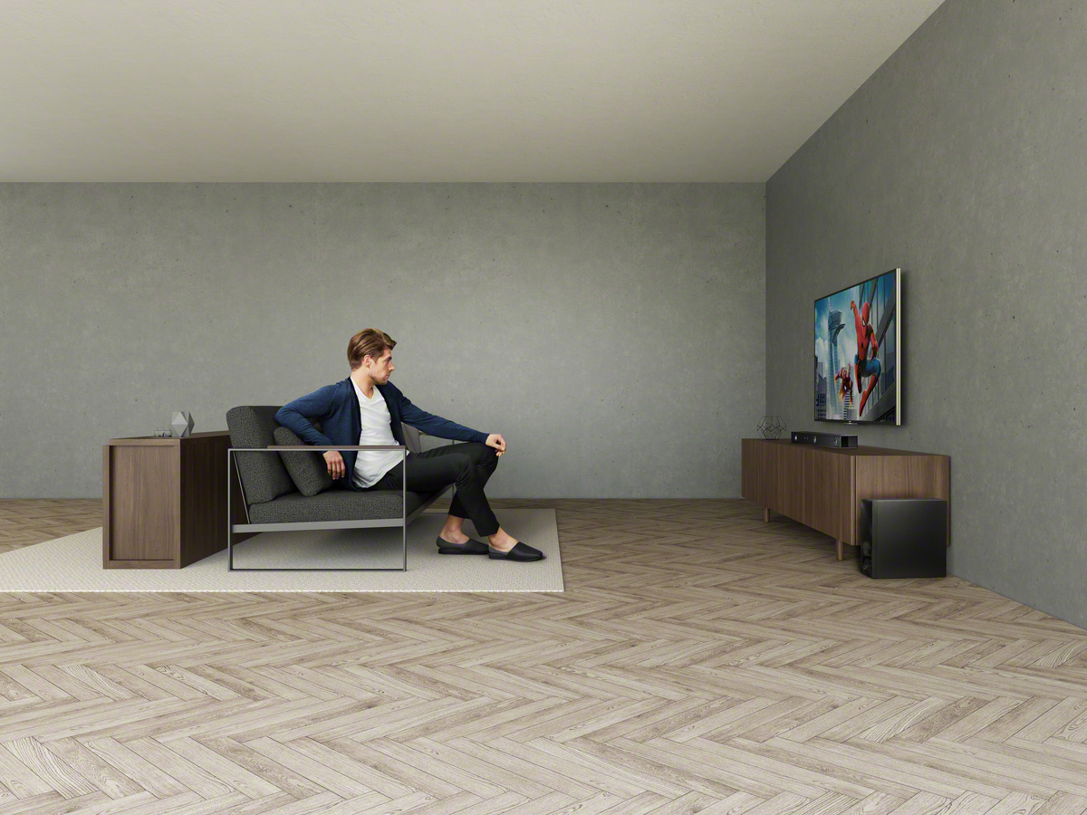 Mann sitzt in einem Raum auf einem Stuhl und sieht fern. Der Fernseher zeigt einen Film.