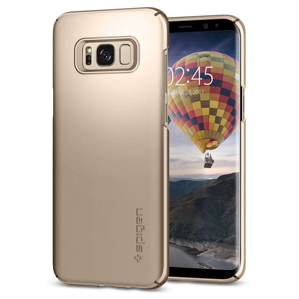 İçinde bir telefon bulunan altın bir telefon kılıfı, tarih ve saati gösteren bir ekran gösteriyor. 'spigen' markası görünür.