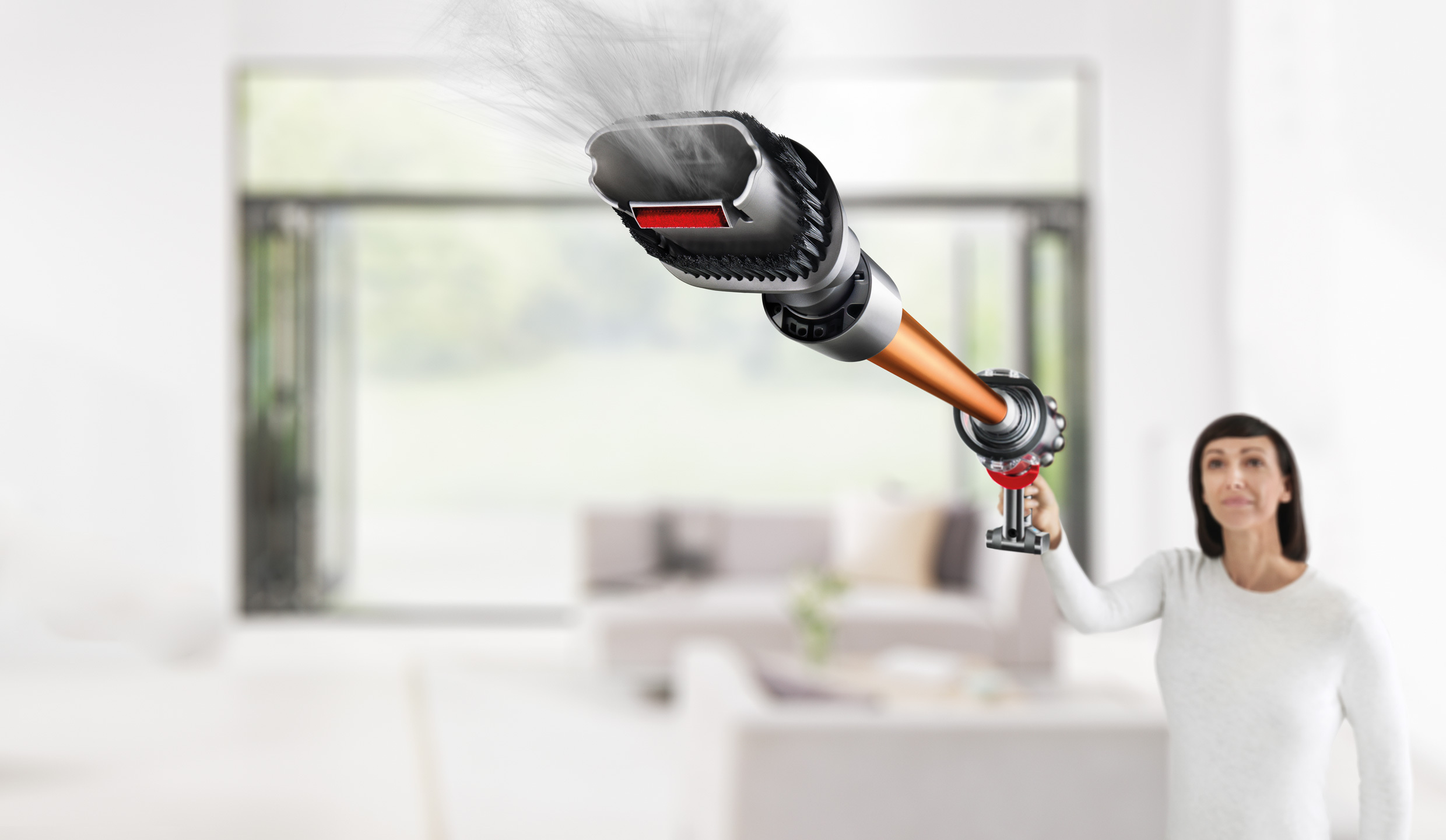 Frau hält Staubsaugerkopf, Luft bläst heraus, unscharfer Raumhintergrund.