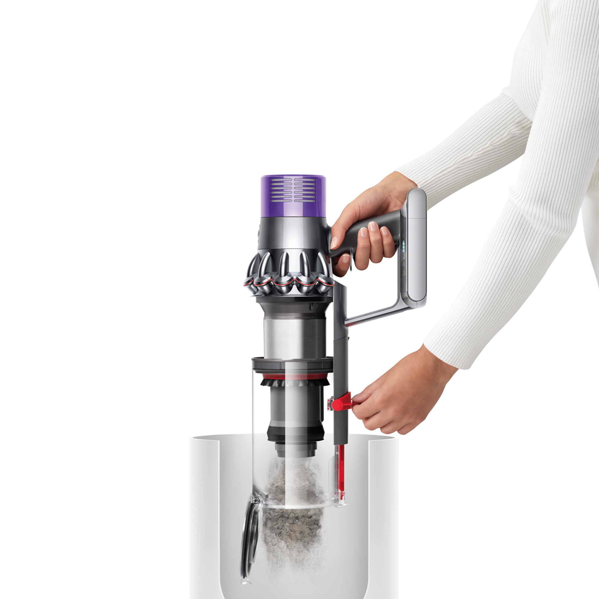 Eine Frau, die einen Dyson-Staubsauger hält. Der Reiniger befindet sich über einem durchsichtigen Behälter.